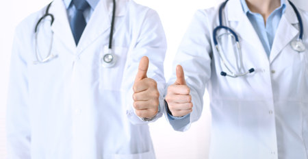 Team of unknown medicine doctors showing OK sign with thumb up close up. Success and high level service in health care, best treatment and customer loyalty and physical conceptの写真素材