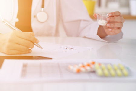 Female medicine doctor fills up  prescription form to patient closeup. Panacea and life save, prescribe treatment, legal drug store, contraception conceptの写真素材
