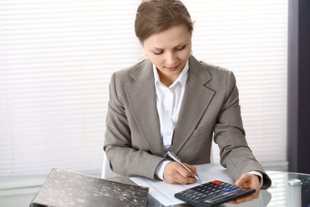 Portrait of female bookkeeper or financial inspector  making report, calculating or checking balance. Copy space areaの写真素材