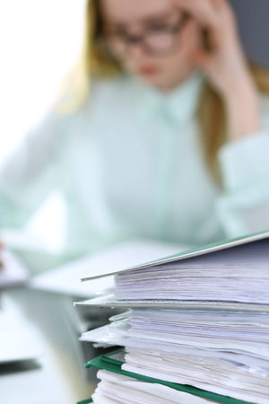 Bookkeeper or financial inspector  making report, calculating or checking balance. Binders with...