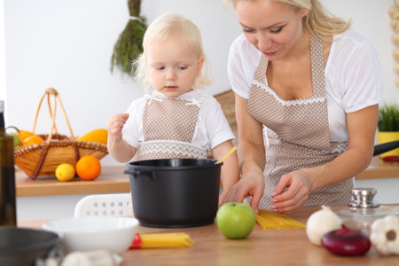 Mother and little daughter  cooking in the kitchen. Spending time all together or happy family conceptの写真素材