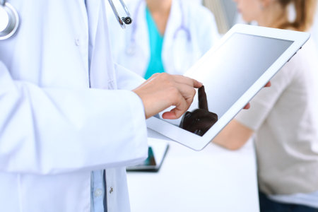 Doctor using tablet computer, close-up of hands at touch pad screenの写真素材