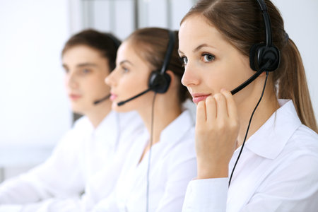 Call center. Focus on beautiful woman in headsetの写真素材