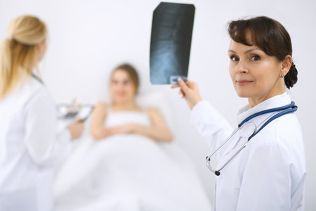 Female doctor smiling on the background with patient and his doctorの写真素材