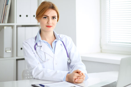 Female doctor sitting at the desk near windowの写真素材