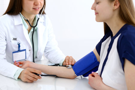 Doctor woman checking blood pressure of female patient, close-up. Cardiology in medicine  and health care conceptの写真素材