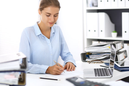 Woman bookkeeper or financial inspector calculating or checking balance, making report. Internal Revenue Service at work with financial document. Tax and audit conceptの写真素材