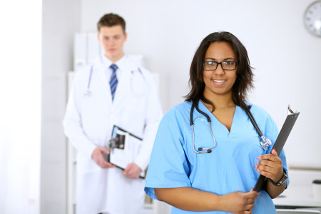 Female african american medical doctor with colleagues in background at hospital. Medicine and health care conceptの写真素材