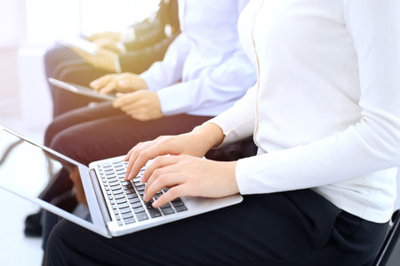 Group of business people sitting in office waiting for job interview, close-up. Hands of woman...
