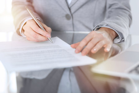 Close-up of female hands with pen over document,  business concept. Lawyer or business woman at work in officeの写真素材