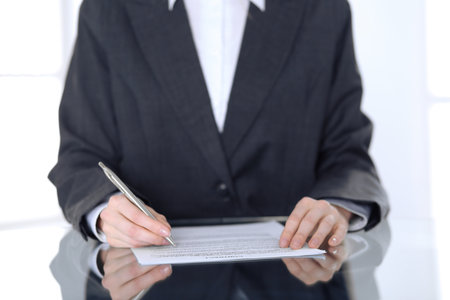 Close-up of female hands with pen over document,  business concept. Lawyer or business woman at work in officeの写真素材