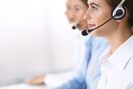 Call center. Group of operators at work. Focus on beautiful business woman in headsetの写真素材