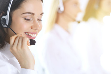 Group of call center operators at work. Focus on beautiful business woman in headsetの写真素材