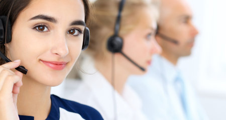 Call center operators at work. Focus at beautiful latin american woman in headsetの写真素材