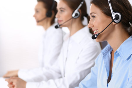 Call center. Group of operators at work. Focus at beautiful business woman in headsetの写真素材