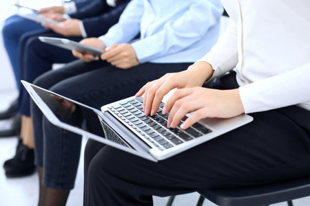 Group of business people sitting in office waiting for job interview, close-up. Hands of woman working on laptop. Conference or training conceptsの写真素材