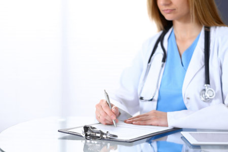 Female doctor filling up medical form on a clipboard, closeup. Healthcare, insurance and medicine conceptの写真素材