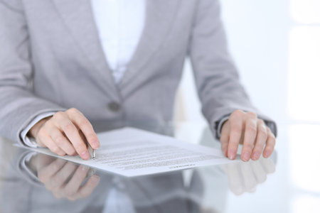 Close-up of female hands with pen over document,  business concept. Lawyer or business woman at work in officeの写真素材