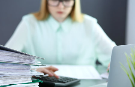 Bookkeeper or financial inspector  making report, calculating or checking balance. Audit and tax service concept. Green colored image backgroundの写真素材