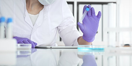 Close-up of professional female scientist in protective eyeglasses making experiment with reagents in laboratory or making blood tests. Medicine, science and research conceptの写真素材