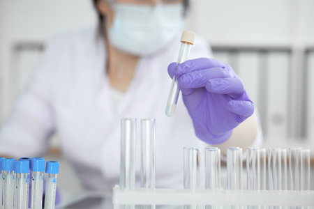 Close-up of professional female scientist in protective eyeglasses making experiment with reagents in laboratory or making blood tests. Medicine, science and research conceptの写真素材