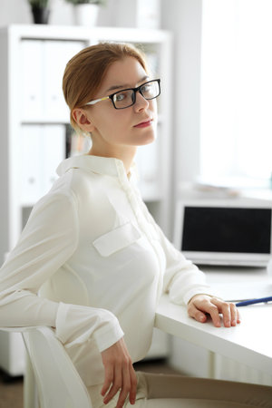 Young brunette business woman looks like a student girl working in office. Caucasian girl happy at work and too busyの写真素材