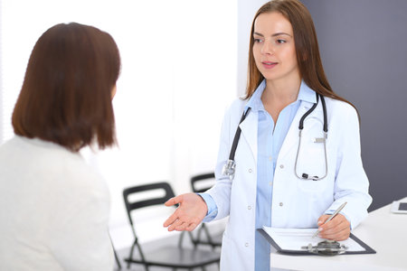 Doctor and  patient  discussing something while standing near reception desk in emergency hospital. Physician at work in clinic. Medicine and health care conceptの写真素材