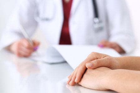 Unknown doctor woman consulting patient while filling up an application form at the desk in hospital. Just hands close-up. Medicine and health care conceptの写真素材