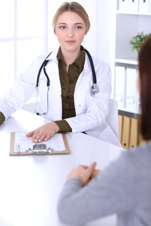 Young woman doctor and patient at medical examination in hospital office. Khaki colored blouse of therapist looks good. Medicine,  healthcare and doctors appointment conceptの写真素材