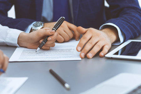 Group of business people and lawyer discussing contract papers sitting at the table, closeup. Businessman is signing document after agreement doneの写真素材