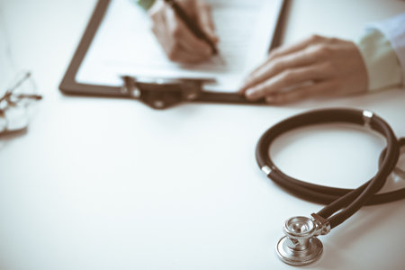 Stethoscope at doctor workplace desk. Physician woman working with medication history records form in clinic. Medicine and health care concept. Green is main colorの写真素材