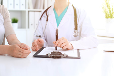 Doctor and patient are discussing something in clinic, just hands at the desk. Medicine and best service conceptの写真素材