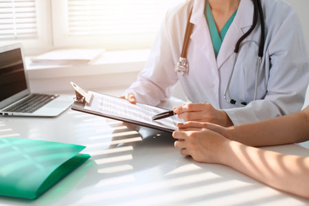 Doctor and patient are discussing something in clinic, just hands at the desk. Medicine and best service conceptの写真素材