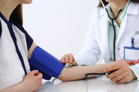Unknown doctor woman checking blood pressure of female patient, close-up. Cardiology in medicine  and health care concept.の写真素材