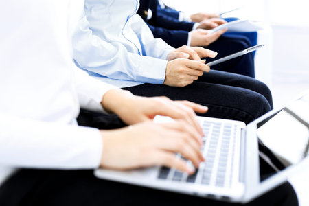 Group of business people sitting in office waiting for job interview, close-up. Hands of woman...