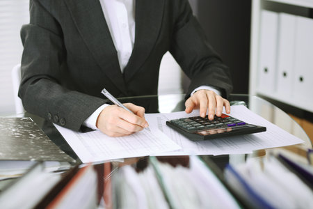 Unknown bookkeeper woman or financial inspector  making report, calculating or checking balance, close-up. Business portrait. Audit or tax concepts.の写真素材