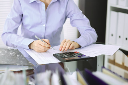Unknown bookkeeper woman or financial inspector  making report, calculating or checking balance, close-up. Business portrait. Audit or tax concepts.の写真素材