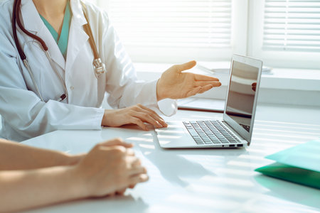 Doctor and patient are discussing something in clinic, just hands at the desk. Medicine and best service conceptの写真素材