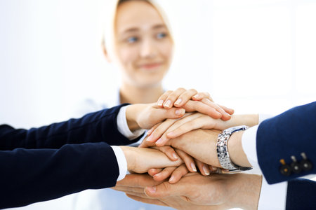 Business team showing unity with their hands together. Group of people joining hands and representing concept of friendship, teamwork and partnershipの写真素材