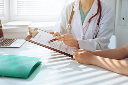 Doctor and patient are discussing something in clinic, just hands at the desk. Medicine and best service conceptの写真素材
