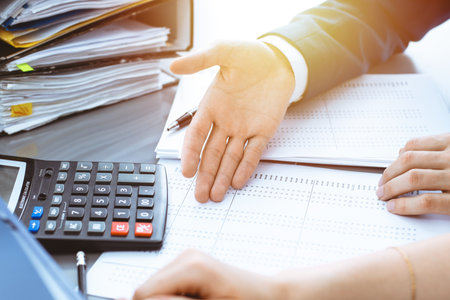 Bookkeeper or financial inspector and secretary making report, calculating or checking balance. Internal Revenue Service inspector checking financial document. Business, tax and audit conceptsの写真素材