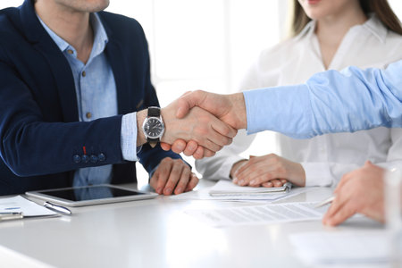 Business people shaking hands at meeting or negotiation, close-up. Group of unknown businessmen and women in modern office. Teamwork, partnership and handshake conceptの写真素材