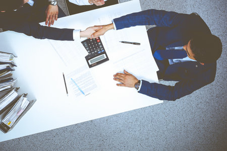 Business people shaking hands at meeting, view from above. Bookkeeper or financial inspector  making report, calculating or checking balanceの写真素材