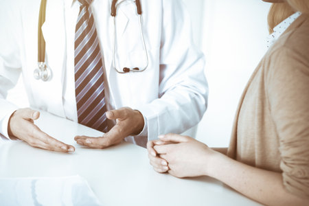 Doctor and patient woman discussing something at the desk in hospital office. Concepts of medical ethics and helping people in medicineの写真素材