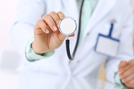 Unknown doctor holds stethoscope head, close-up. Medical help and insurance in health care, best treatment and medicine conceptの写真素材