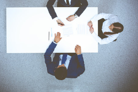 Group of business people and lawyer discussing contract papers sitting at the table, view from above. Businessman is signing document after agreement doneの写真素材