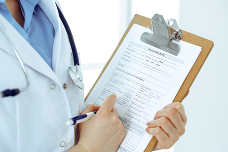 Female doctor using medical form on clipboard closeup. Physicianat work in hospital or clinic. Healthcare, insurance and medicine conceptの写真素材