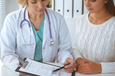Happy blonde female doctor and patient discussing medical examination results. Medicine, healthcare and help conceptの写真素材