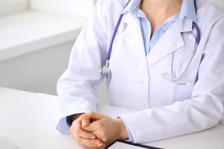 Female doctor sitting at the desk near window. Medicine and health care concept.の写真素材