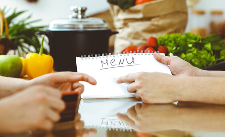 Closeup of human hands discussing something while cooking in kitchen. Women talking about menu. Family dinner, friendship and lifestyle concept.の写真素材